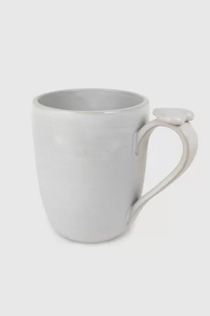 Tasse en grès blanc mat avec cœur sur l'anse pour une touche d'amour. Faite à la main, elle ajoute sophistication à votre pause café ou thé.